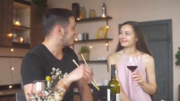 Feliz pareja apasionada comiendo sushi y bebiendo vino tinto en casa, cámara lenta — Vídeo de stock