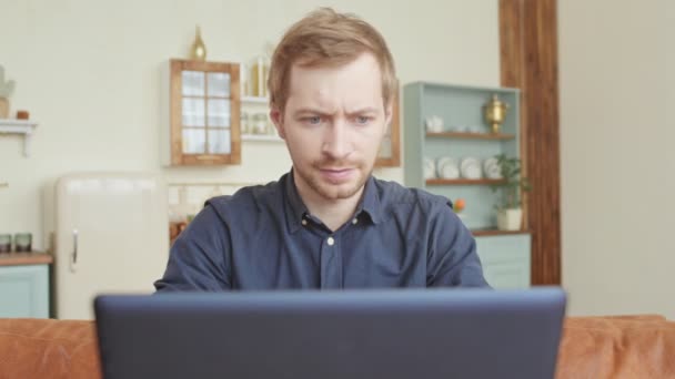 Jonge gestresste knappe man werkt aan een bureau in de woonkamer schreeuwen op laptop scherm en boos — Stockvideo