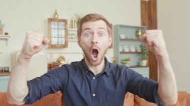 Elleri havada heyecanlı sıradan bir adamın portresi başarıyı kutluyor ve kameraya bakıyor.