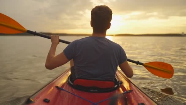 Reunión puesta de sol en kayaks. Vista trasera del joven kayak en el lago con puesta de sol en el fondo — Vídeo de stock