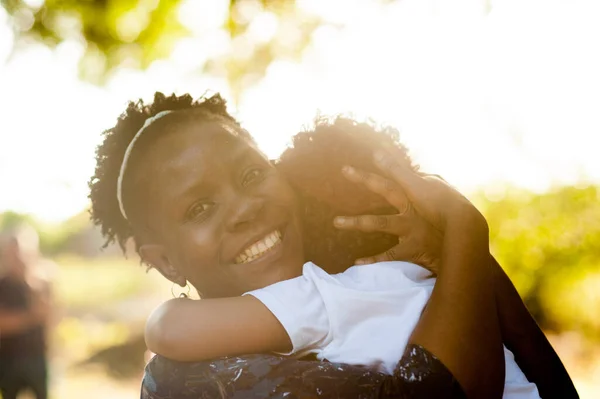 African mom smiling to the camera  holding her toddler boy in her arms. Great copy spcace.