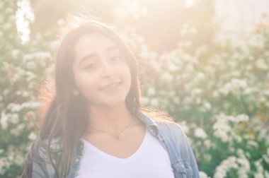 Çiçek açan arka planda beyaz bir kız. Mercek parlaması