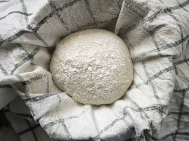 Geleneksel ev yapımı ekşi ekmek sepeti. Pişirmeden önce mutfakta çay havlusuyla kaplı.
