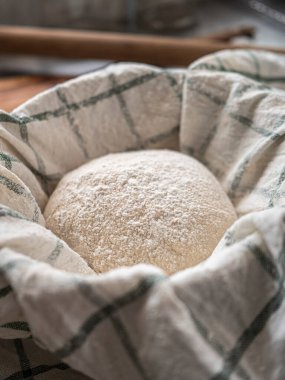 Geleneksel ev yapımı ekşi ekmek sepeti. Pişirmeden önce mutfakta çay havlusuyla kaplı.