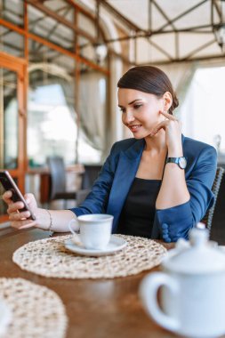 Mavi takım elbiseli bir iş kızı, restoranda dinleniyor.