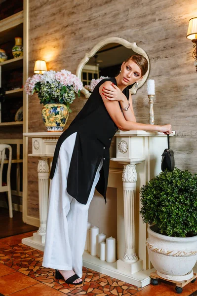 A girl in an evening dress with trousers in a restaurant. Demonstration of clothing