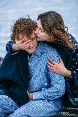 Donmuş gölün buzunda pijamalı bir adam ve bir kız. Adam demir bir yatakta oturuyor, yanındaki kız..