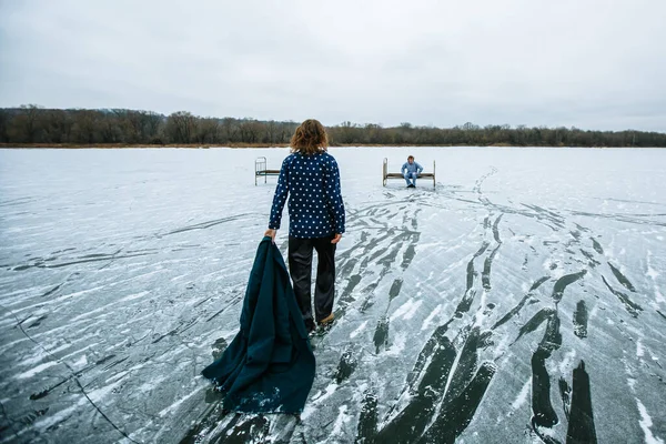 A guy and a girl in pajamas on the ice of a frozen lake. The girl goes to the guy in the snow.