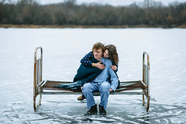 寒冷な湖の氷の上に パジャマ姿の男と女がいる 人々は氷の上の鉄のベッドの上に座る — ストック写真