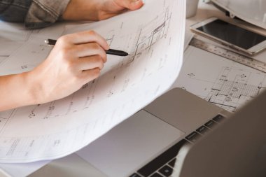 Mühendisler elinde planlı bir binayı işaret eden bir kalem tutuyorlar ve proje planlamak için bir bilgisayar kullanıyorlar. Mühendislik ve inşaat konsepti.
