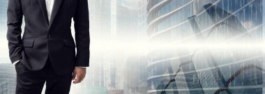 Modern ofis geçmişinde eli pantolonunun içinde duran bir iş adamı..