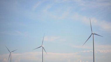 Güneşli bir günde mavi gökyüzü ve beyaz bulutlu rüzgar türbinleri veya rüzgar enerjisi dönüştürücüleri. Yeşil ekolojik dünya için yenilenebilir enerji üretimi..