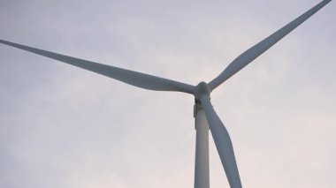 Gün batımında dönen bir rüzgar türbinini kapatın. Yeşil ekolojik dünya için yenilenebilir enerji üretimi.