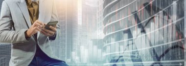 Bar grafikli ve şehir planlı telefonu kullanan bir iş adamı.