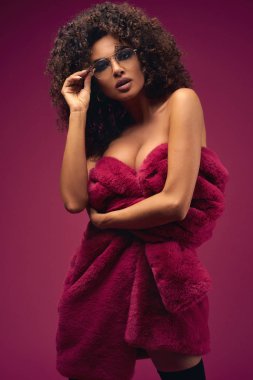 Parlak bir arka planda bir kürk ceket yarım çıplak model