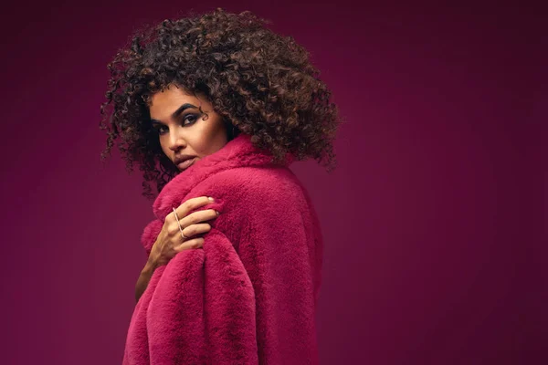 portrait of a curly model in a fur coat on a bright background