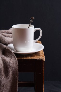 Koyu anahtar yakın eşarp ile eski ahşap koltukta Beyaz fincan