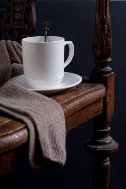 Koyu anahtar yakın eşarp ile eski ahşap koltukta Beyaz fincan