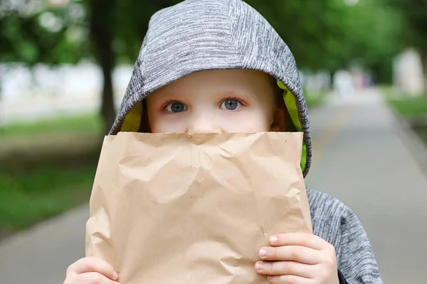 Lustigt blondheared barn äter georgiskt bröd med aptit på gatan.Håller sin i papper hantverk paketet. Närbild fotografering av roliga boy.Copy utrymme för text. — Stockfoto