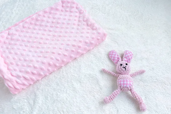 Pink blanket for baby girl and toy on a white fur carpet. Newborn Baby Concept. Baby Girl Clothes Set.