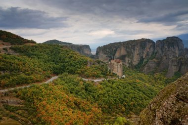 Güzel manzara, Rousanou St. Barbara Ortodoks Manastırı, muazzam monolitik sütun, yeşil ve sarı yapraklar Meteora, Pindos Dağları, Thessaly, Yunanistan 'daki taş duvarın arka planında.