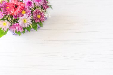 Beyaz ahşap arka planda sepetin içinde güzel bir çiçek buketi..