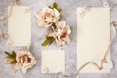 Düğün davetiyesi kağıtları güllerle süslenmiş olarak masanın üzerinde duruyordu.