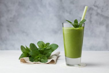 Sağlıklı bir içki. Gri arka planda muz, avokado, ıspanak ve limonlu meyve suyu..