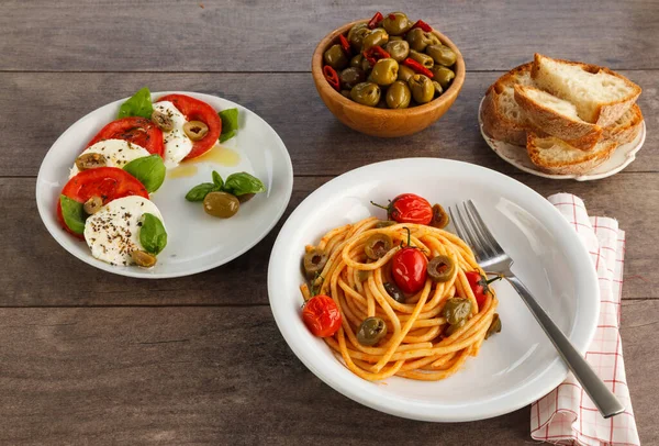 プレート上のイタリア料理の完全なテーブル スパゲッティ カプレーゼ オリーブとパン — ストック写真
