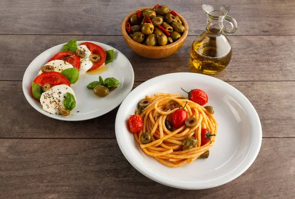 プレート上のイタリア料理の完全なテーブル スパゲッティ カプレーゼ オリーブとオリーブオイル — ストック写真