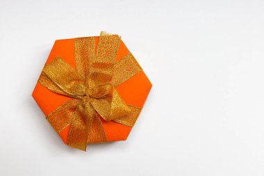 Güzel bir turuncu altıgen kutu, kurdeleli ve beyaz arka planda fiyonk. Düz yatıyordu. Metin için yer