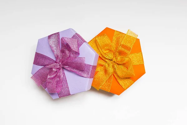 Una hermosa naranja y cajas de regalo de hexágono lila con cinta y lazo en el fondo blanco. Acostado. Lugar para el texto. Presente. —  Fotos de Stock