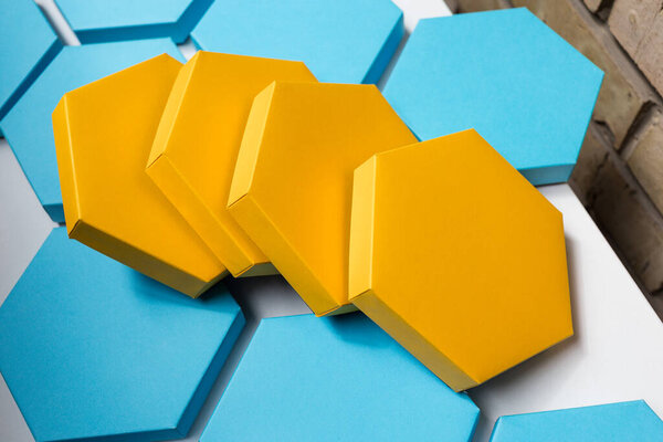 A close up beautiful blue and yellow hexagon boxes of present on the white background. Place for text. Empty centre. Top view. Flat lay. Mockup