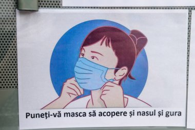 Bükreş, Romanya - 6 Haziran 2020: Coronavirus salgınının (COVID-19) yayılmasını hafifletmek amacıyla, bir mağazaya girişte tıbbi koruma maskesinin zorunlu olduğunu gösteren poster sergileniyor