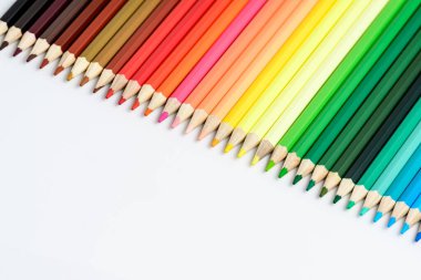 Çapraz sıraya dizilmiş ve beyaz, çocuk okulu ya da ofis tedarikçilerinden oluşan bir grup karışık renkli kalem yan görünüşten hafifçe fotoğraflanmış, metin için boşluk bırakılmış.