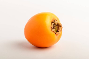 Bir taze organik olgun portakal kaki ya da masada hurma meyvesi, beyaz arka planda izole edilmiş, lezzetli sağlıklı vejetaryen yemeğinin yumuşak odaklı yan görüntüsü.