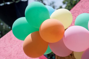 Çocuk parkında renkli balonlar, doğrudan güneş ışığında, sarı, turuncu, pembe ve yeşil balonlar.