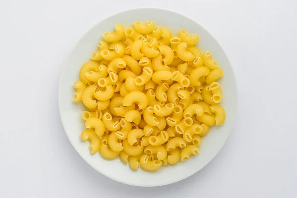 乾燥したコルネッティRigatiイタリアのパスタは テーブルの上に白いプレートに表示され 調理する準備ができて 白い背景に隔離され トップビューまたは健康的な食べ物の平らなレイアウト写真 — ストック写真