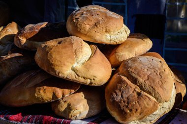 Bir sokak gıda pazarında satışa sunulan taze pişmiş tahıllı ekmek yığını, yumuşak odaklı sağlıklı yiyecekler.