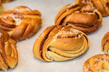 Taze sıcak tarçın ruloları beyaz yemek kağıdında, ev yapımı ve yenmeye hazır, sıcak sarı ışıkta yumuşak bir odak ile fotoğraflanmış.