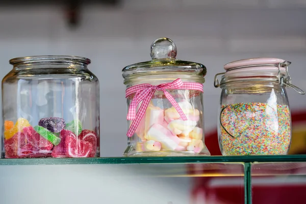 Trzy Szklane Słoiki Kolorowymi Słodyczami Cukierki Pianki Posypki Służące Dekoracji — Zdjęcie stockowe