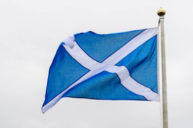 İskoçya Bayrağı (Saltire veya Saint Andrew Haçı) Yağmurlu bir günde bulutlu gri gökyüzüne doğru esen rüzgarda 