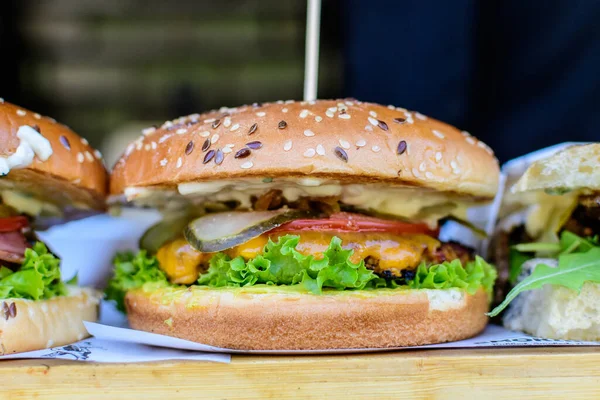 Close up of a tasty hamburger sandwich, with grilled spiced meat with tomato, salad, and bacon,  displayed for sale at an weekend street food market, selective focus
