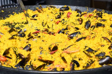 Geleneksel İspanyol paella tabağı. Bir sokak yemeği festivalinde geleneksel siyah bir tavada pişmiş. Deniz ürünleri yemeye hazır.