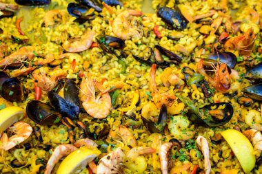 Geleneksel İspanyol paella yemeğinin büyük bir kısmını kapatıyoruz. Bir sokak yemeği festivalinde deniz ürünleri, yan görüş ve seçici bir odak noktasında deniz ürünleri ve makarna ile kızartılıyor.