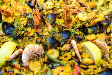 Geleneksel İspanyol paella yemeğinin büyük bir kısmını kapatıyoruz. Bir sokak yemeği festivalinde deniz ürünleri, yan görüş ve seçici bir odak noktasında deniz ürünleri ve makarna ile kızartılıyor.