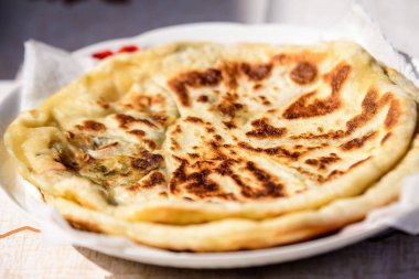 Taze pişirilmiş geleneksel tatlı peynir turtası, bir sokak yemeği pazarında satışta, yumuşak bir odak ile fotoğraflanmış.