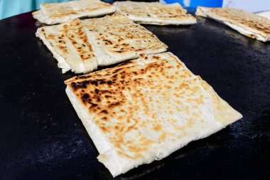 Et ya da peynirle doldurulmuş ve levha demirinde pişirilmiş düz ekmekten yapılmış olan gözleme adlı geleneksel Türk yemeği, bir sokak gıda pazarında satılmaya hazırlanıyor.