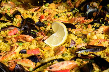 Geleneksel İspanyol paella yemeğinin büyük bir kısmını kapatıyoruz. Bir sokak yemeği festivalinde deniz ürünleri, yan görüş ve seçici bir odak noktasında deniz ürünleri ve pilav ile kızartılıyor.