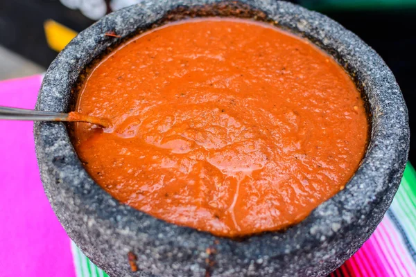 Spiced red tomato salsa for seasoning traditional Mexican food at a street food market, selective focus